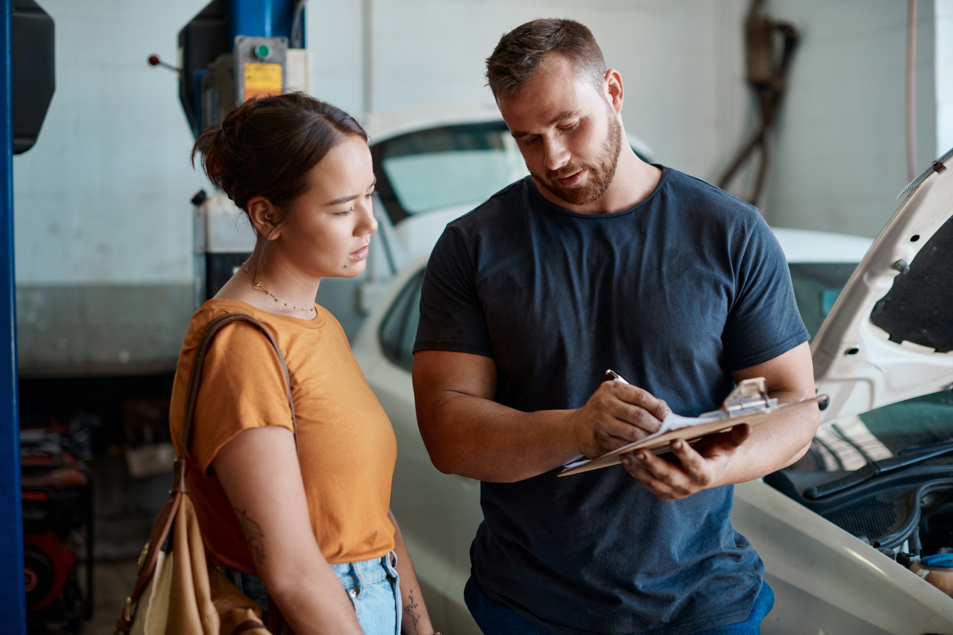 Shot of a woman talking to a mechanic in an auto repair shop